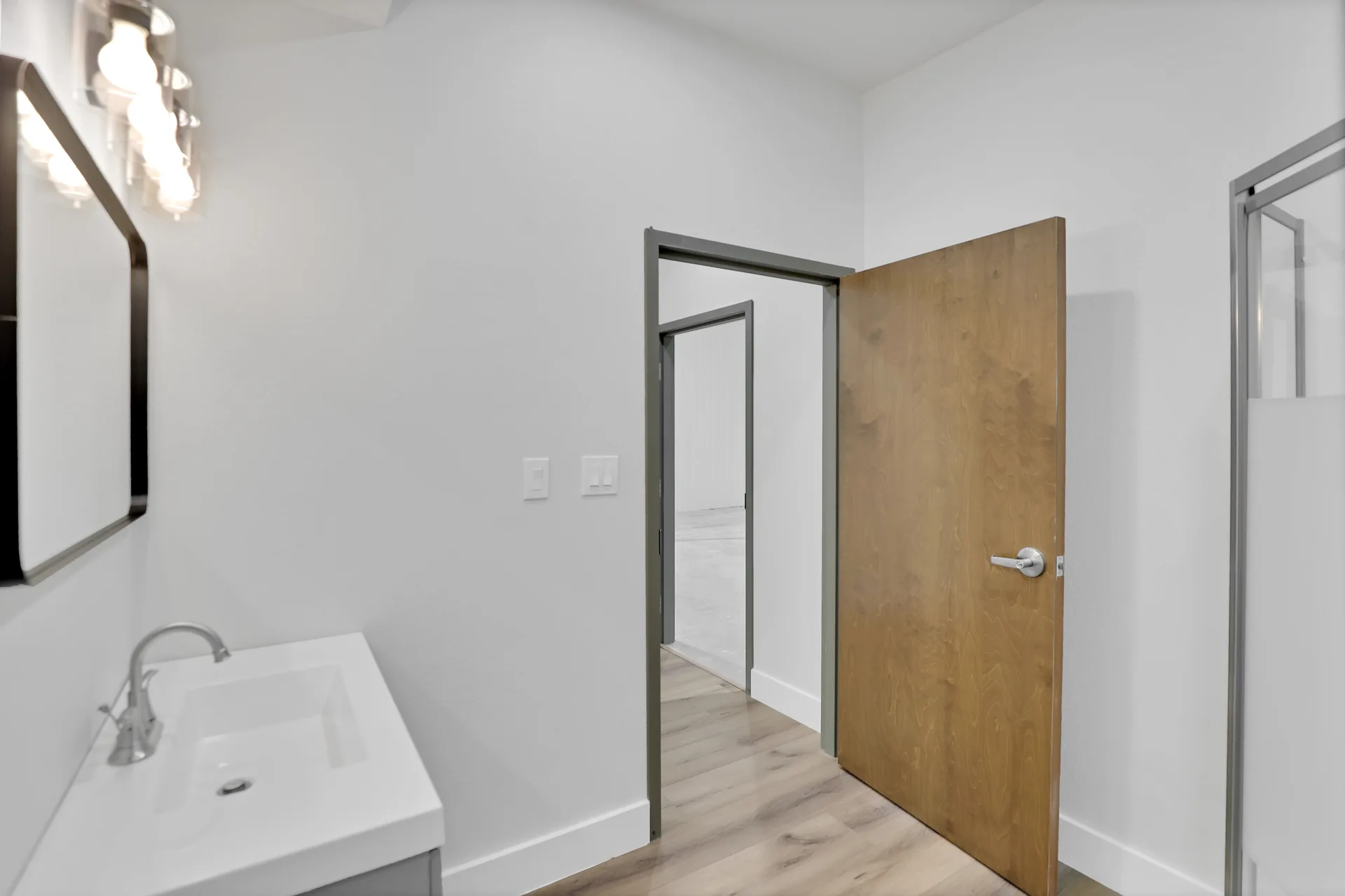 Bathroom amenity with vanity, mirror, open door, and shower access inside a Triple C Business Park unit
