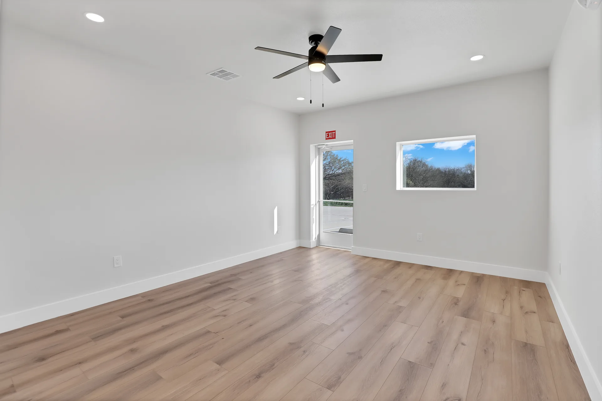 Bright Triple C Business Park office area with exterior glass entry door, window, ceiling fan, and wood-look flooring
