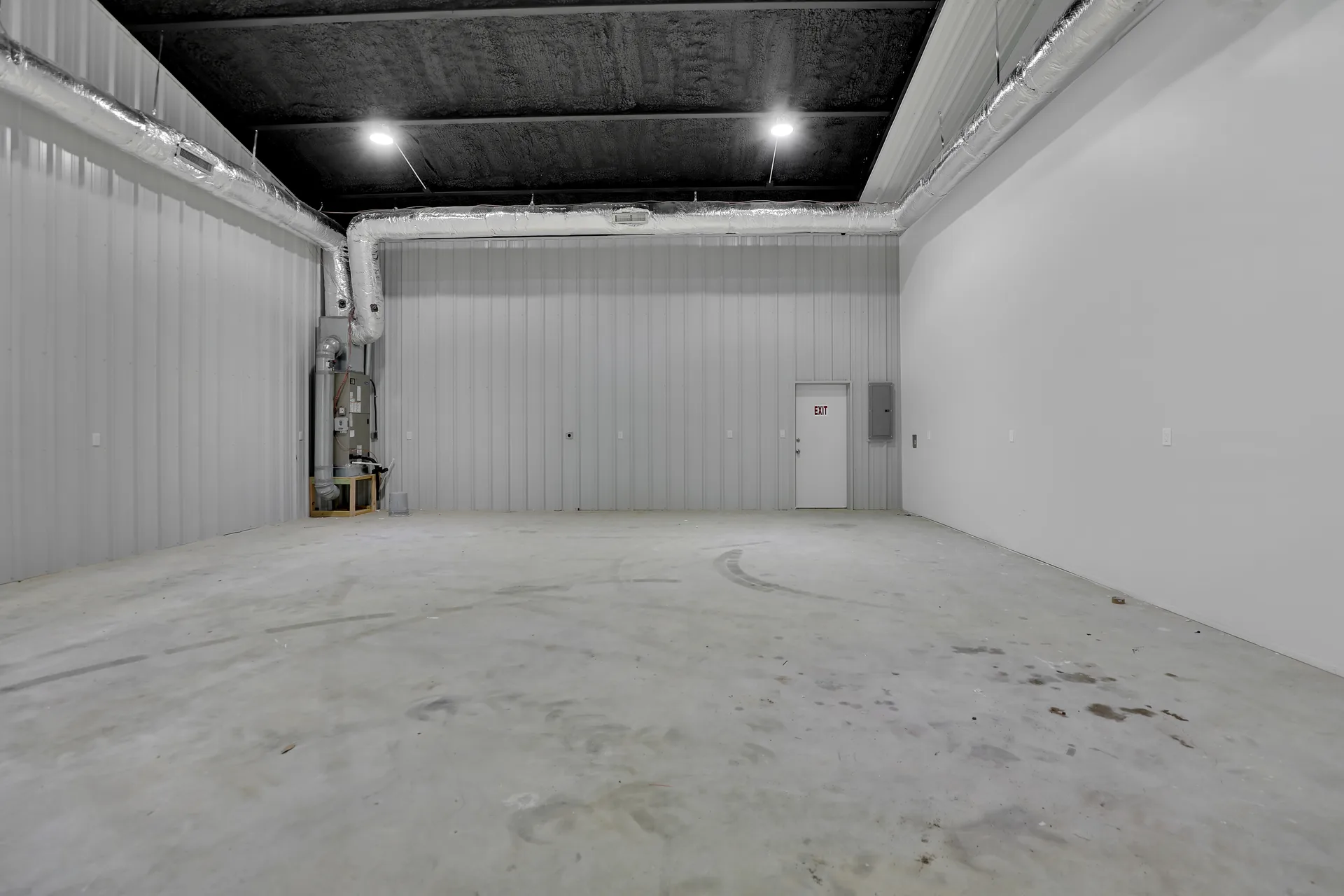 Open warehouse bay at Triple C Business Park with concrete floor, metal walls, high ceiling, and personnel door