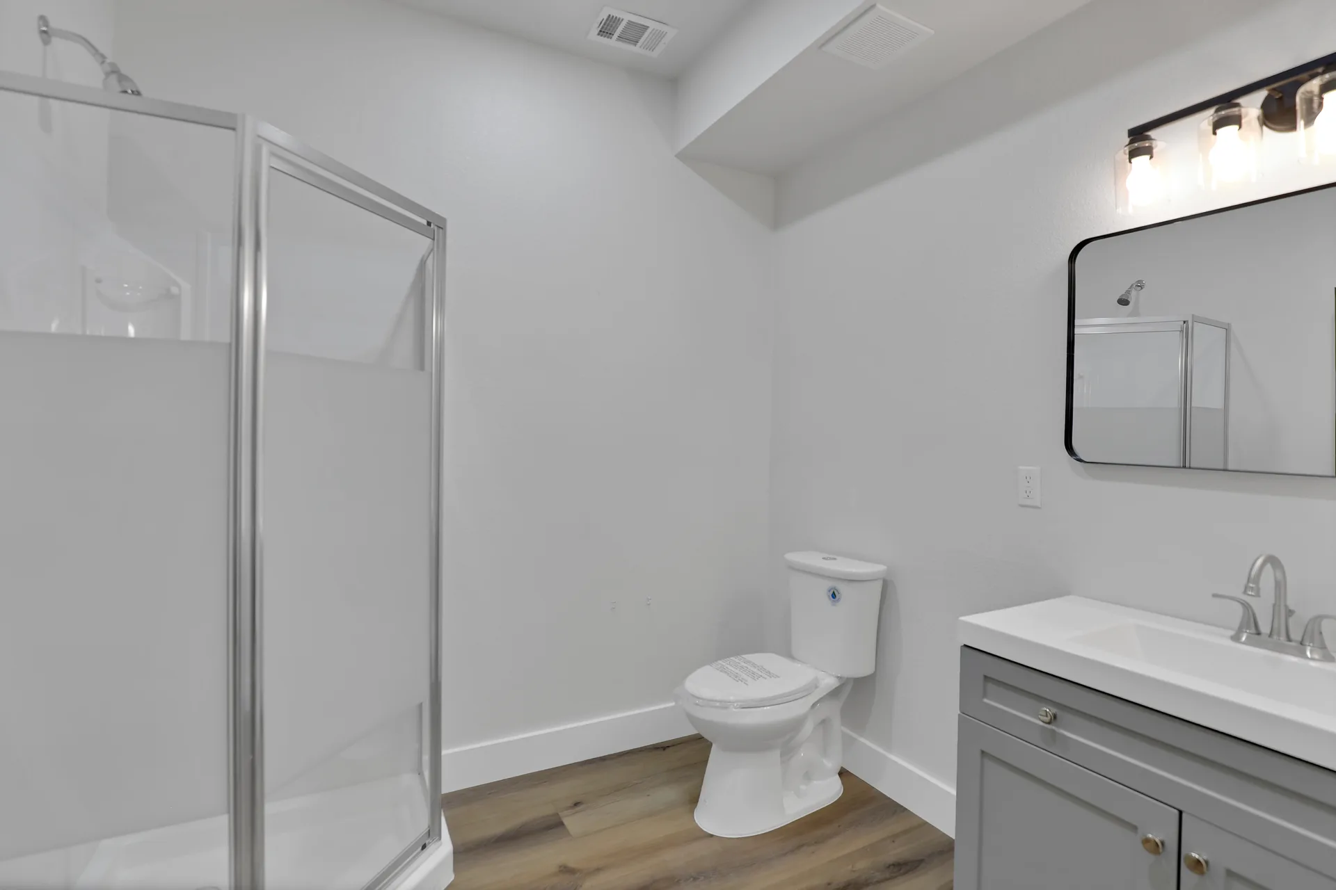 Restroom at Triple C Business Park with vanity, toilet, mirror, lighting, and shower stall